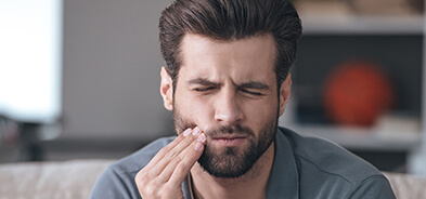 Young man holding the side of his mouth with dental pain