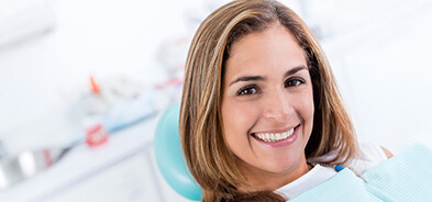 Woman sitting in dental chair grinning to show her clean and healthy teeth