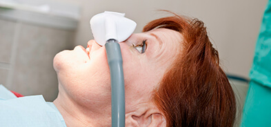 Female patient lying in dental chair with sedation mask on her face