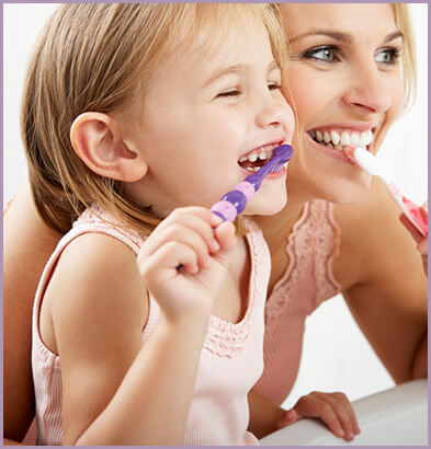 Mother teaching her daughter how to brush her teeth