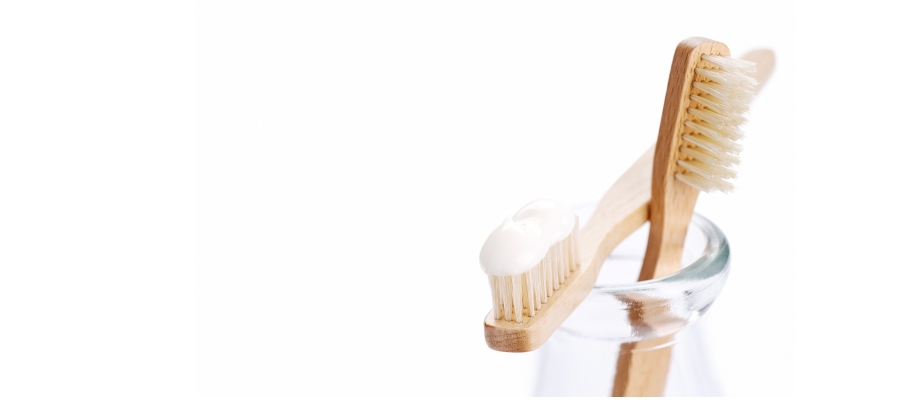 two wooden toothbrushes in jar with organic toothpaste