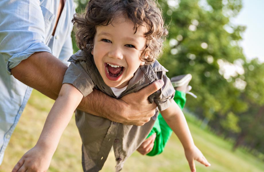 young boy with baby teeth playing outside with dad