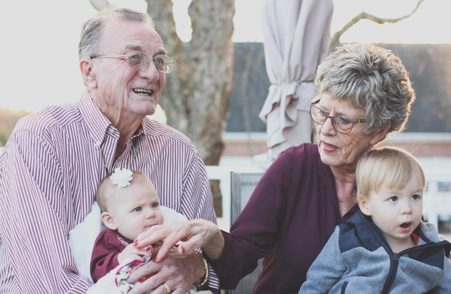 A grandma and grandpa hold their two grandkids