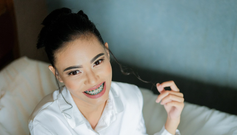 girl smiling twirling her hair wearing braces on her teeth