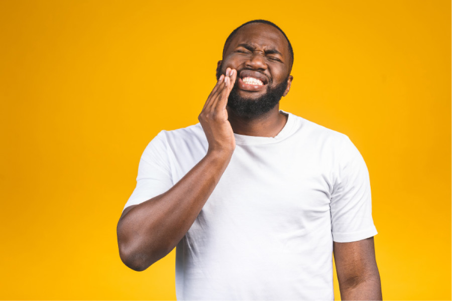 man holds his jaw in pain with a severe toothache