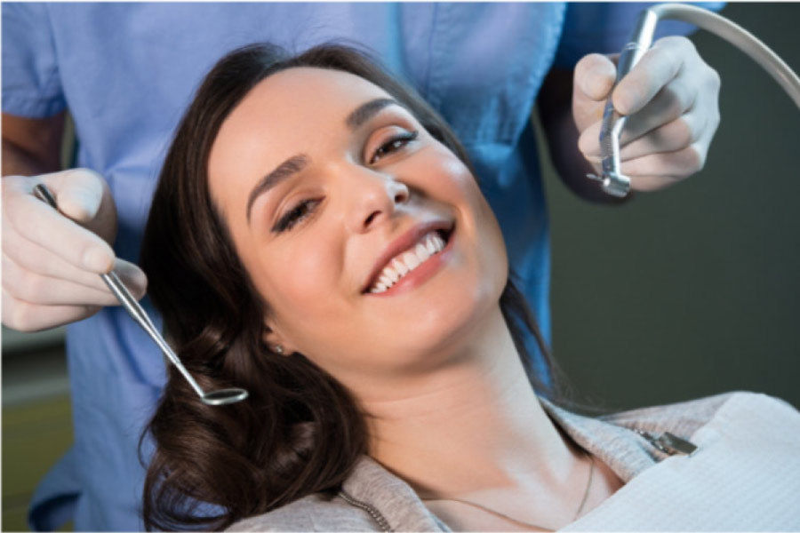 young woman smiles in the dentist chair after a teeth cleaning