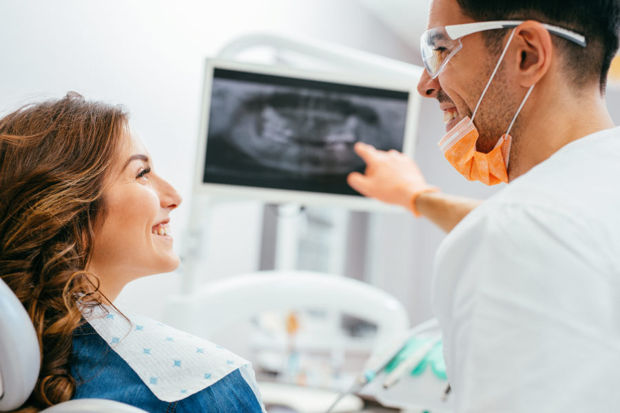 woman looks at dental x-rays with the dentist