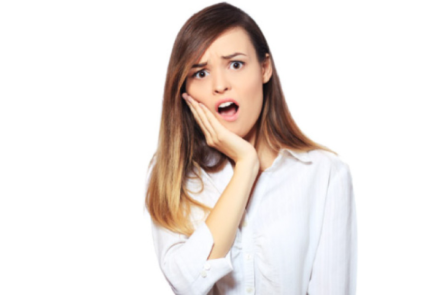 young woman holds her jaw in surprise after losing a crown