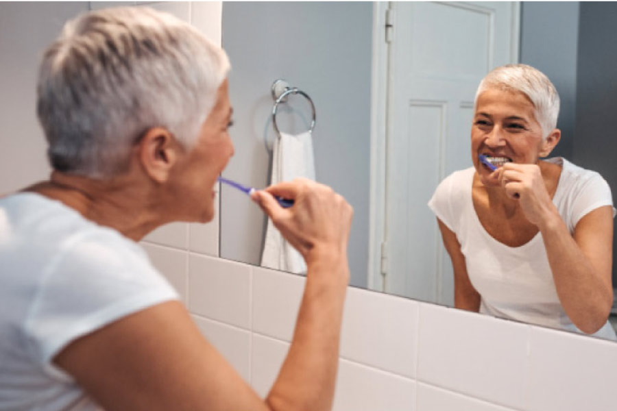 senior woman brushes her teeth with a soft toothbrush to combat sensitive teeth