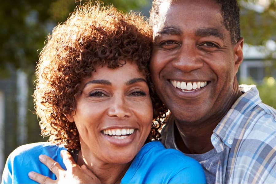 couple hug and smile showing off their porcelain veneers